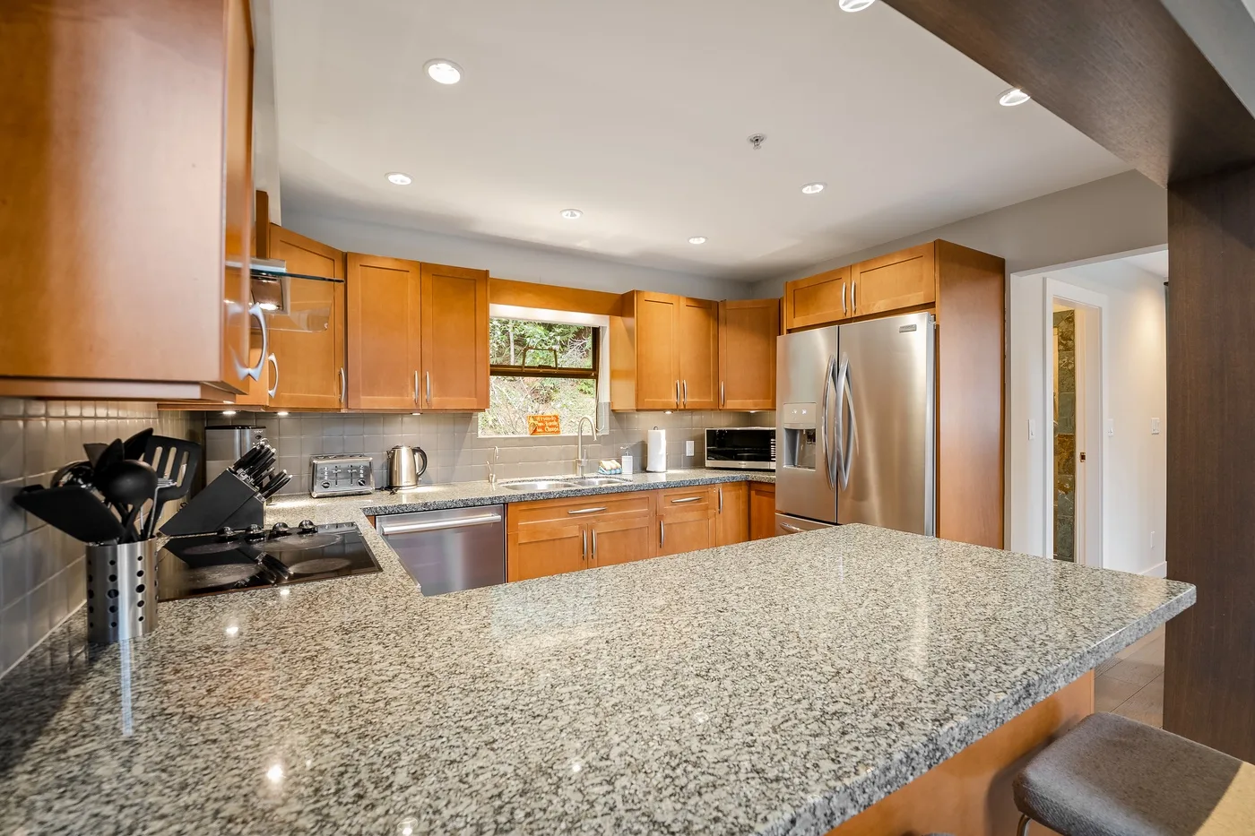 Una cocina amplia con gabinetes de madera y una gran isla de granito.