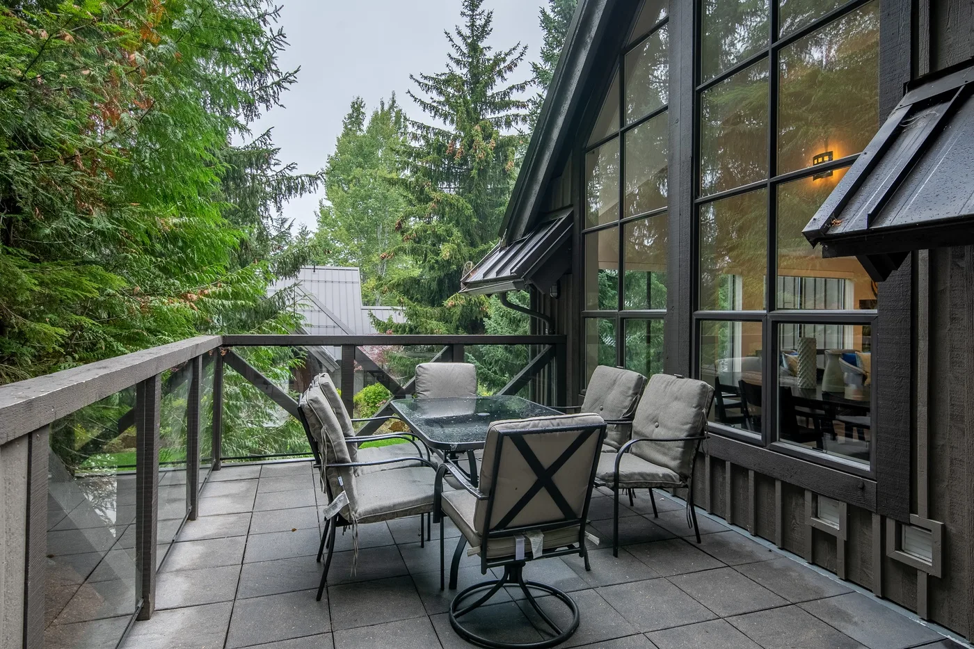 Un patio exterior con una mesa de comedor y asientos junto a grandes ventanas.