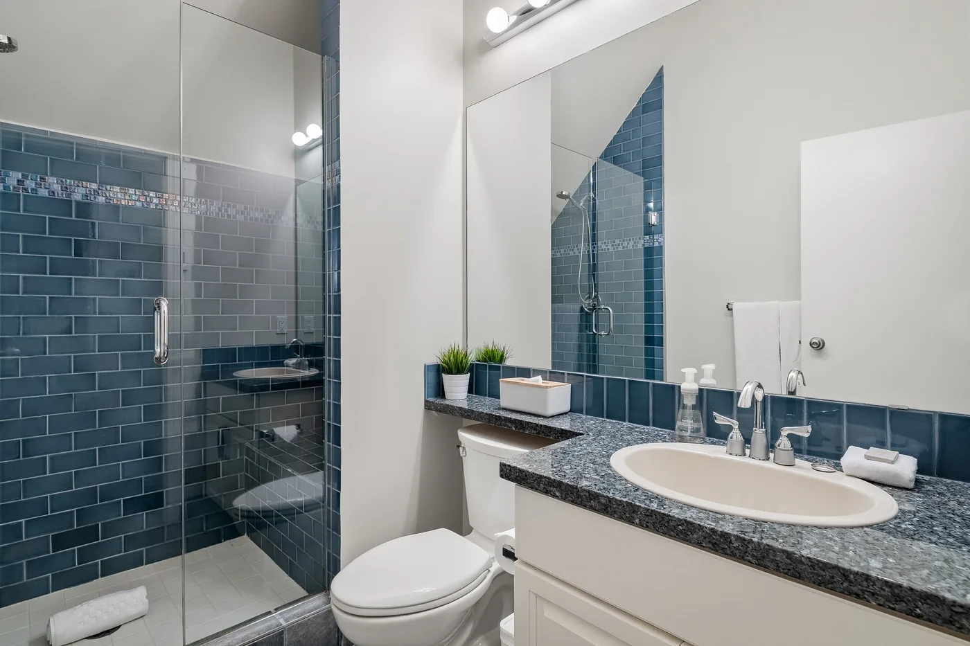 Un baño alicatado con ducha de vidrio, inodoro y tocador.
