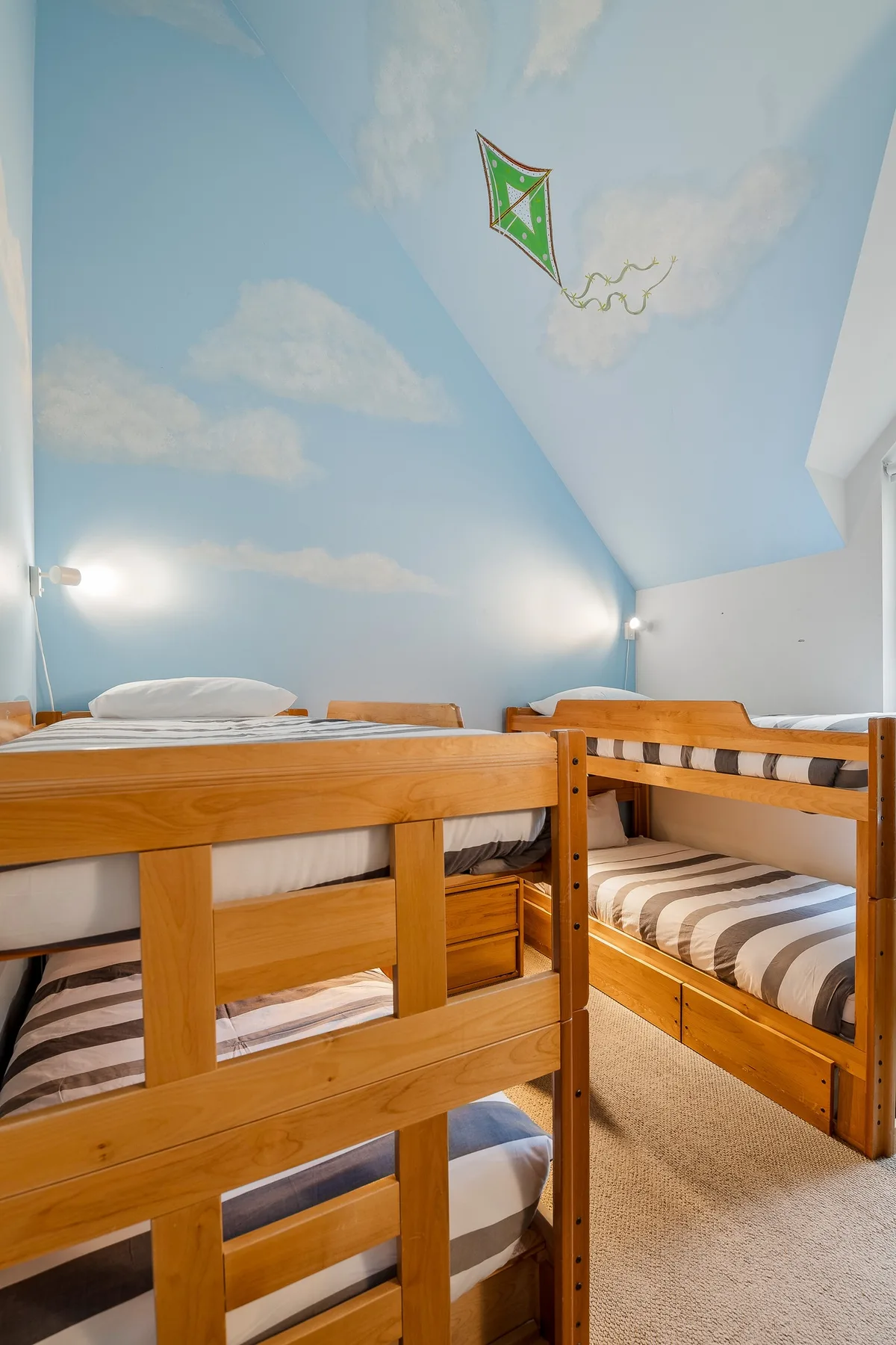 Un dormitorio con literas de madera y un techo pintado como el cielo.