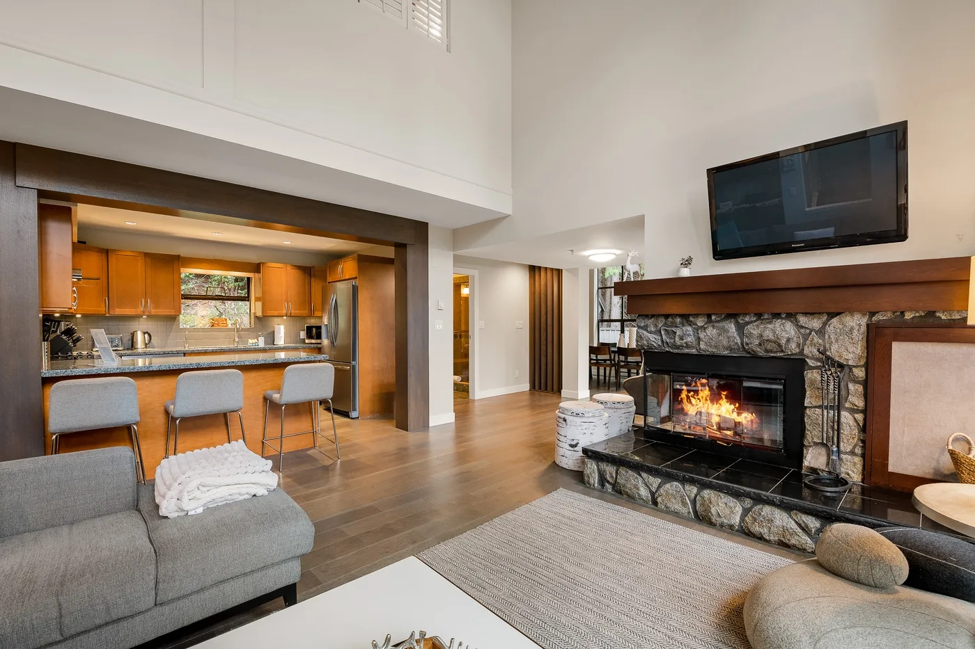 Sala de estar y cocina abiertas, con asientos y una chimenea de piedra.