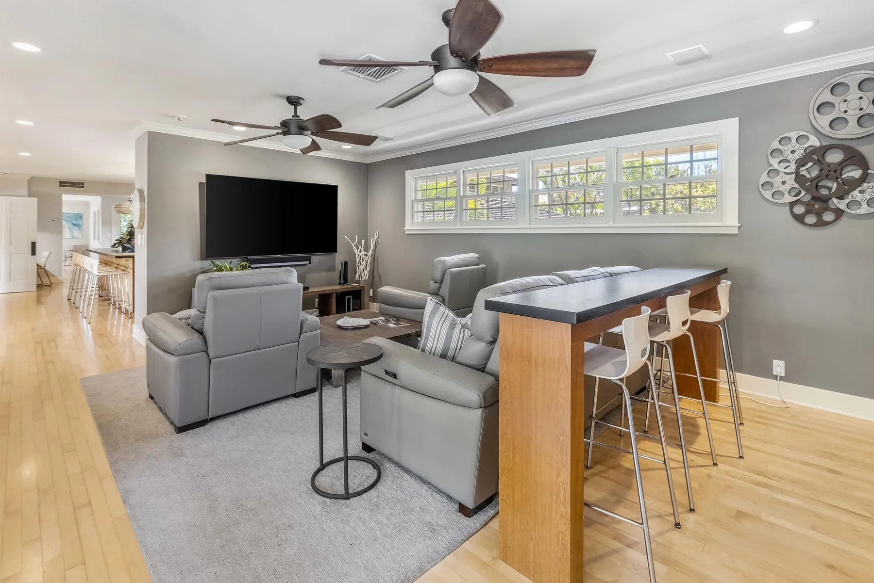 An open living room with gray seating, a television, and a breakfast bar.