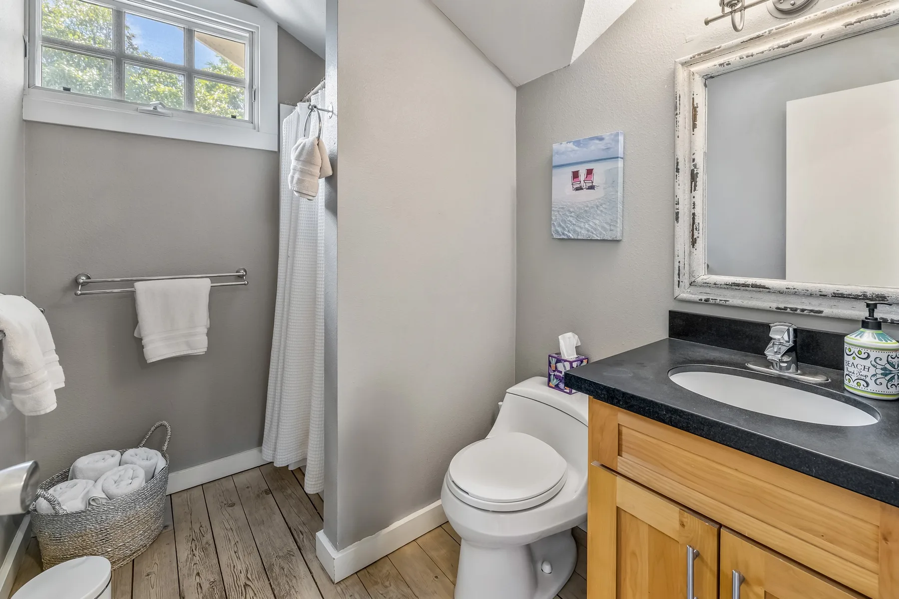 A bathroom with a toilet, sink, and towels beside a high window.