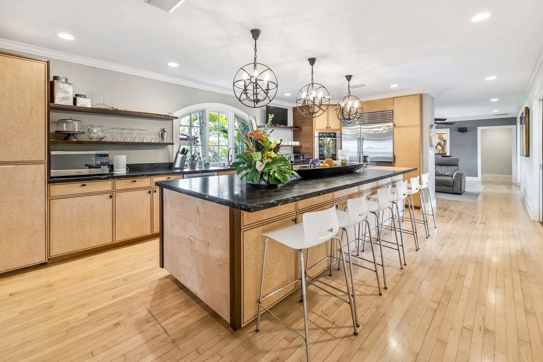A bright kitchen with a large island, bar seating, and pendant lights.