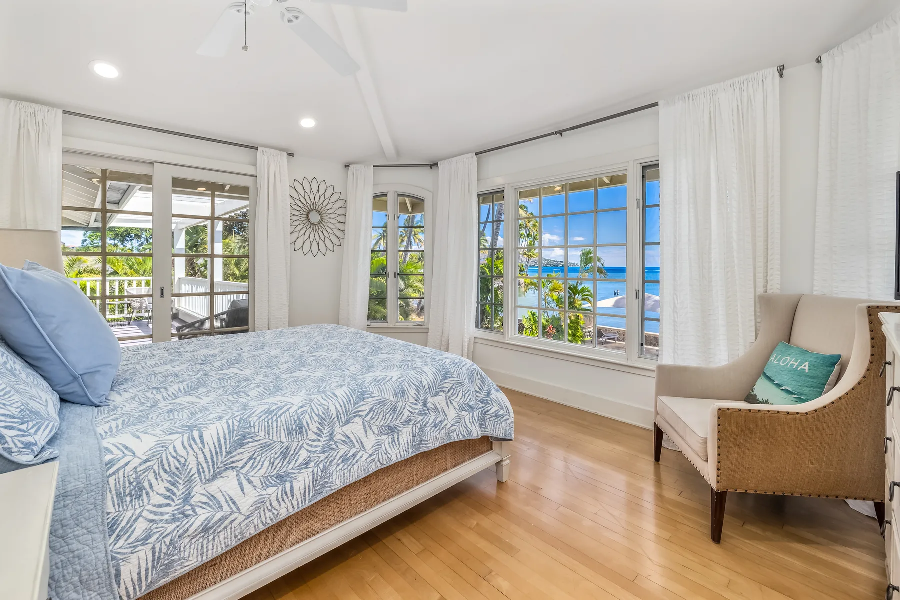 A bright bedroom with a bed and large windows overlooking the water.