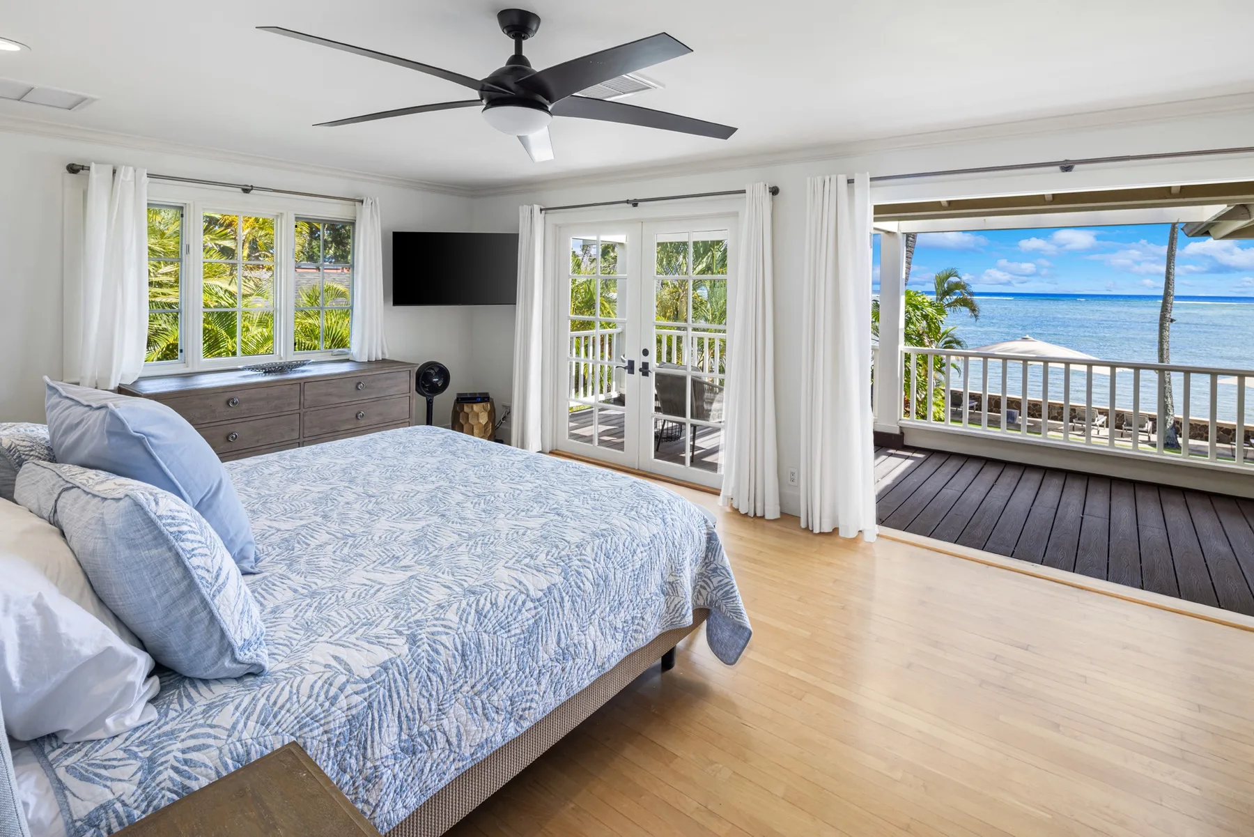 A bedroom with a bed, sliding glass doors, and an ocean view.