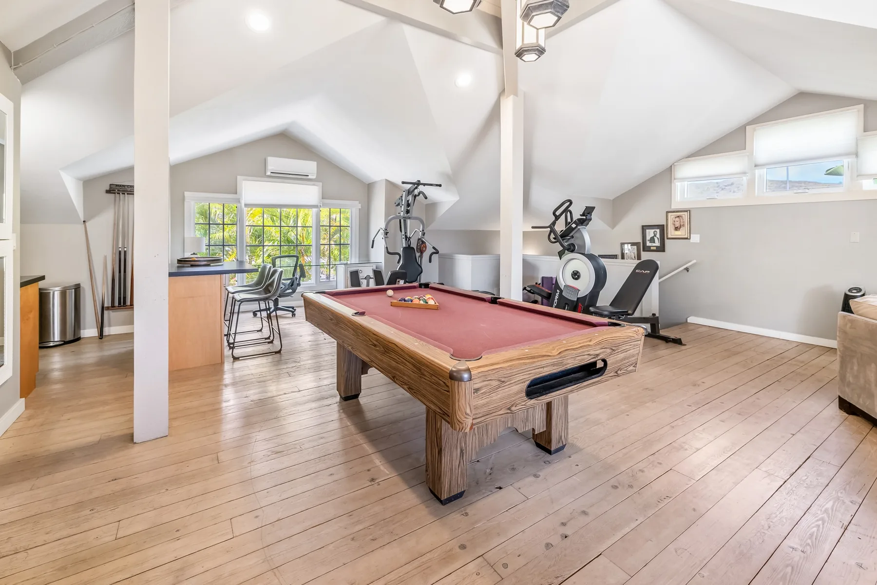 A spacious recreation room features a pool table and exercise equipment.