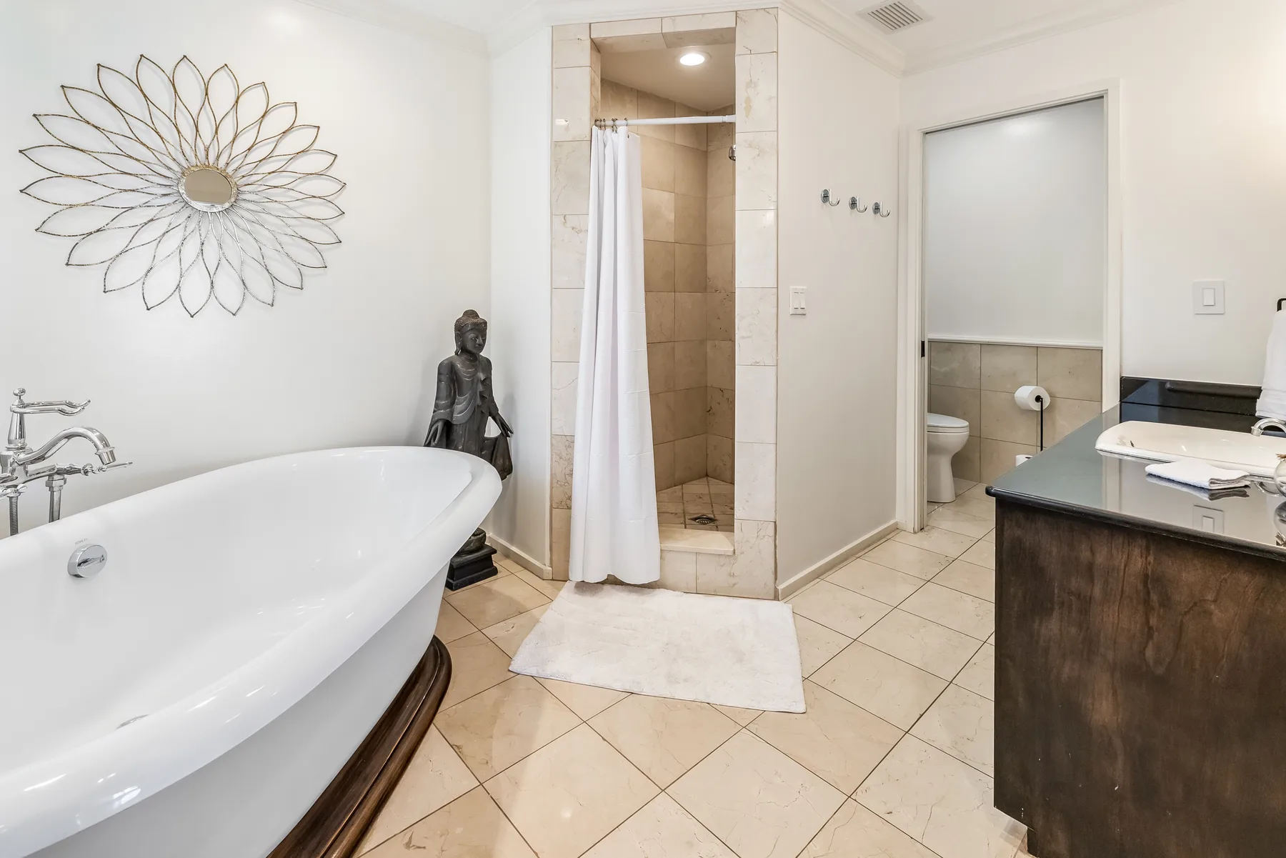 A bathroom with a freestanding bathtub and a curtained shower.