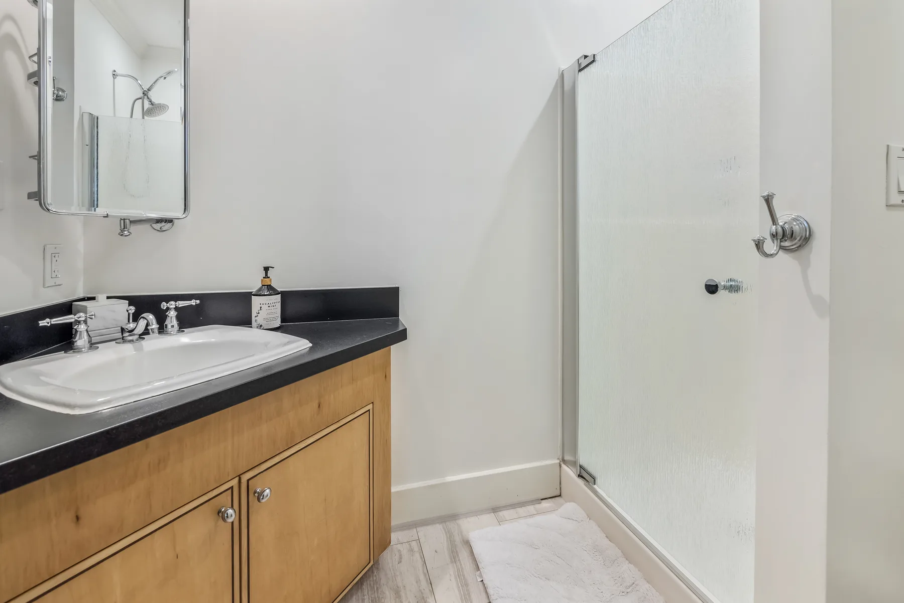A bathroom with a sink, vanity, and shower.