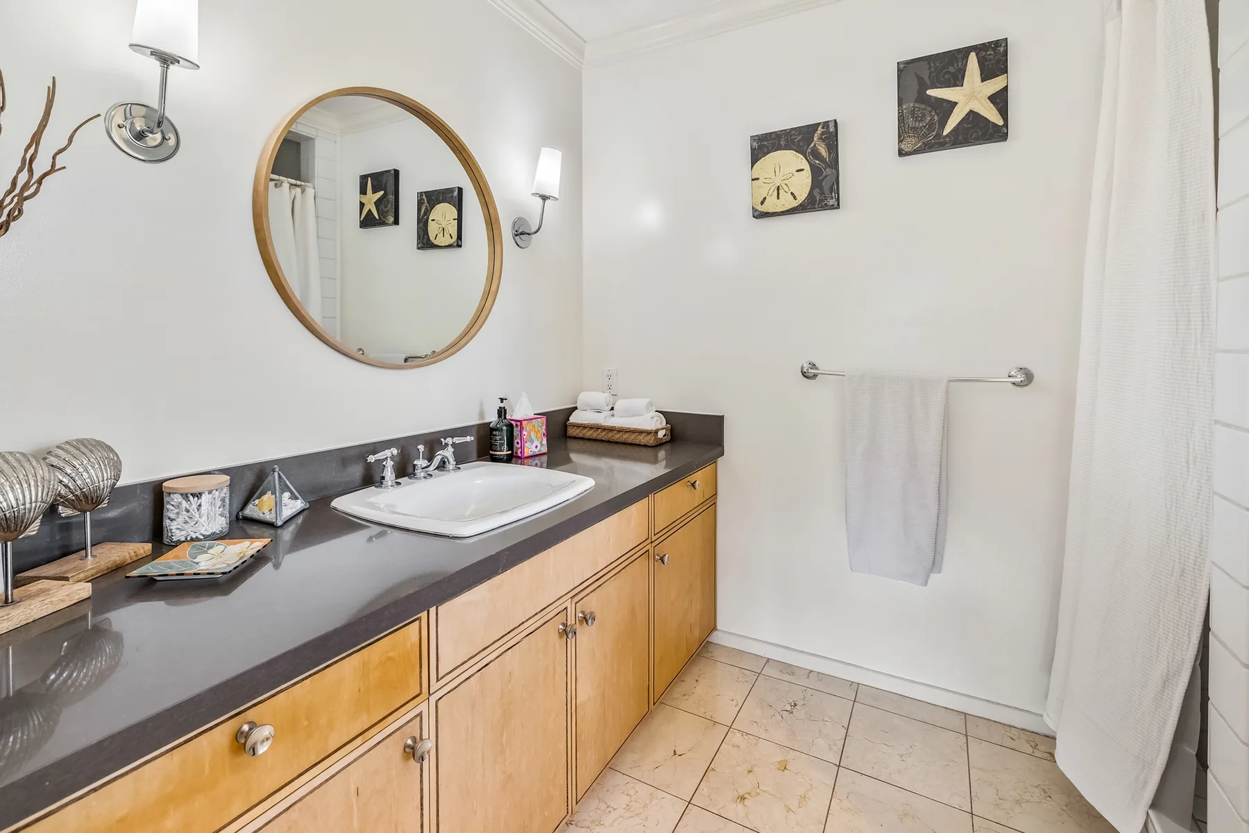 A bathroom vanity with a sink and mirror stands beside a towel bar and shower curtain.