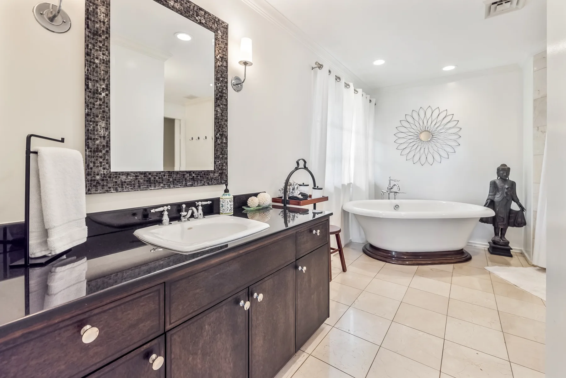 A bright bathroom with a freestanding bathtub and a long vanity.