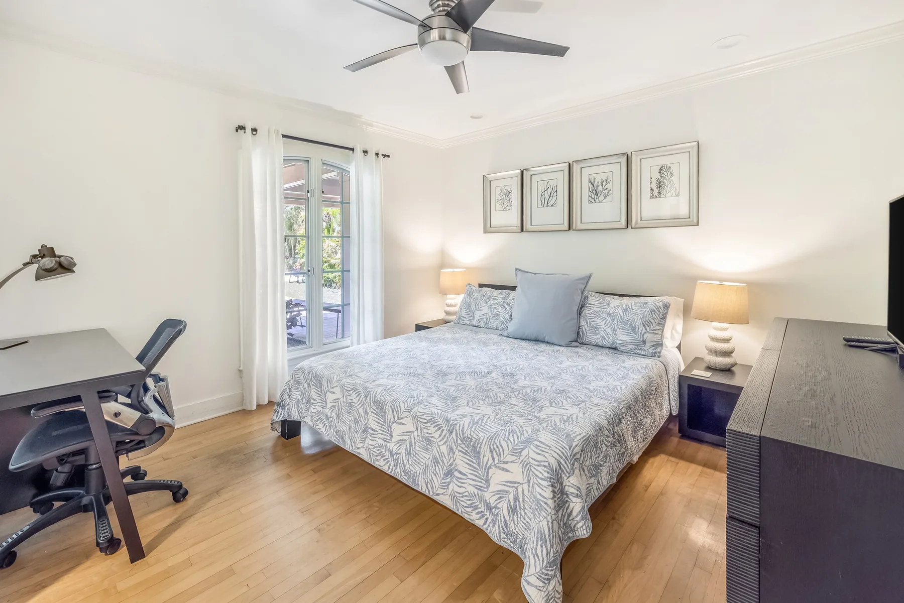 A bedroom with a bed, bedside lamps, and a desk by the window.