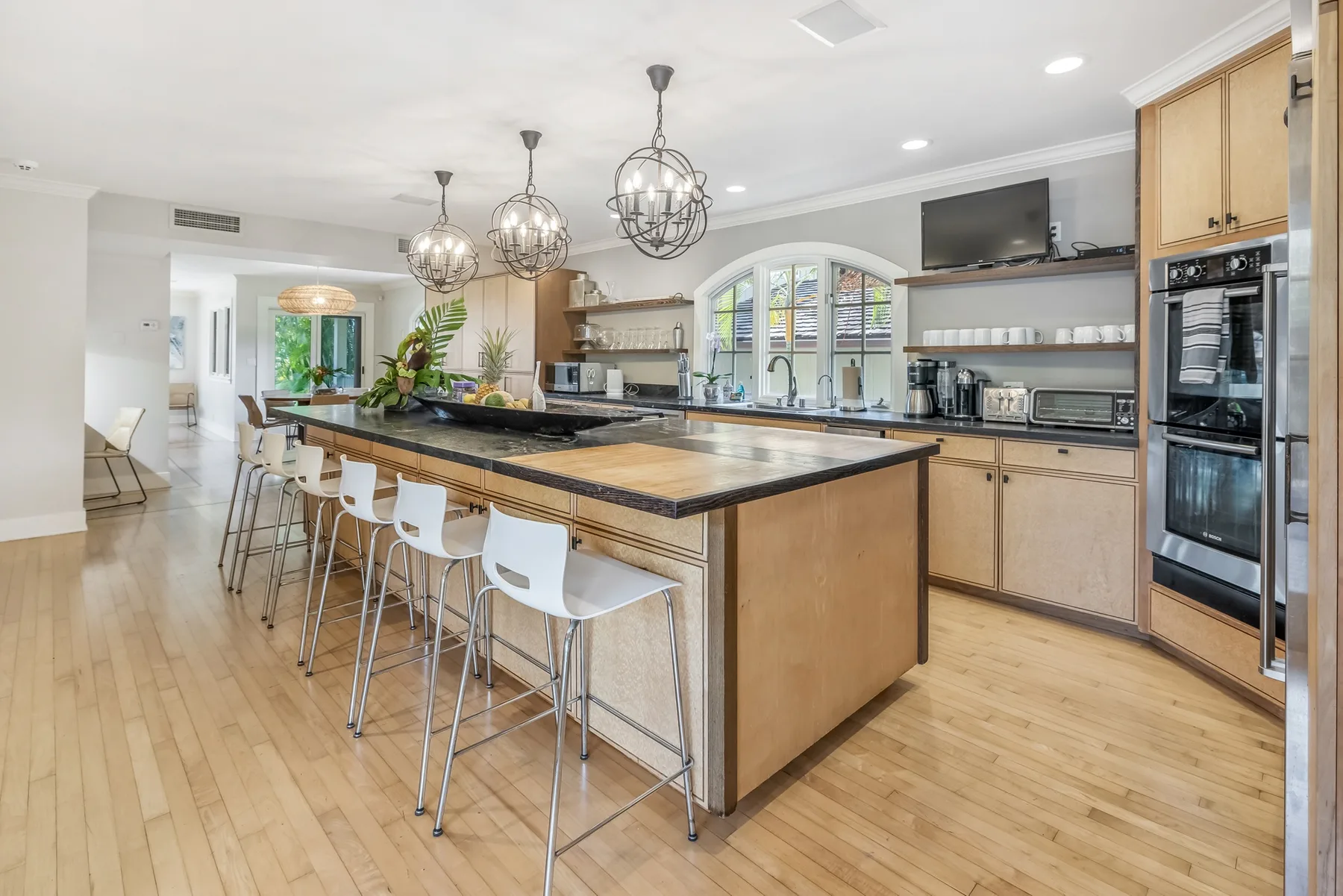 A bright kitchen with a large island and seating along its counter.