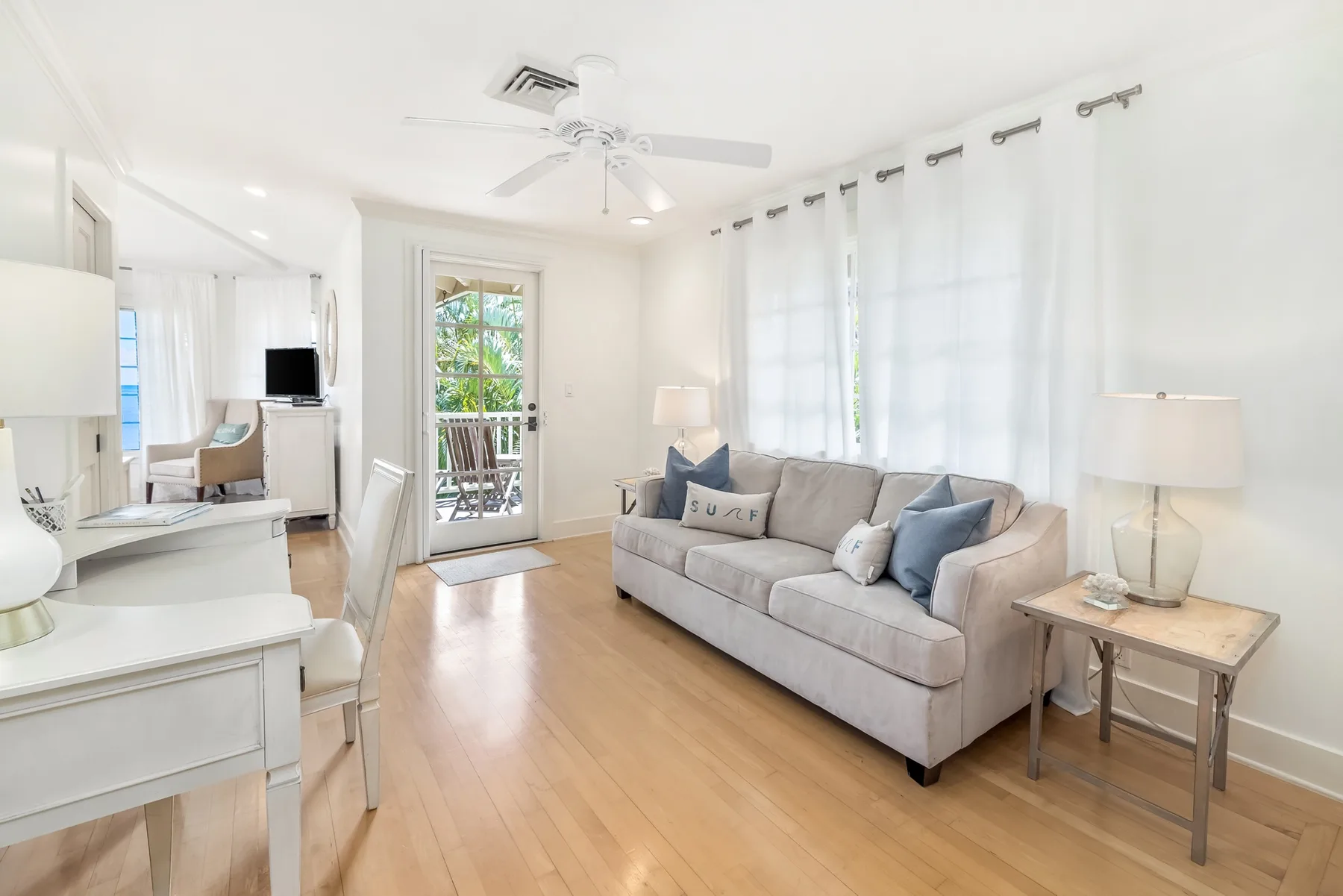 A bright living room with a sofa beside large curtained windows.