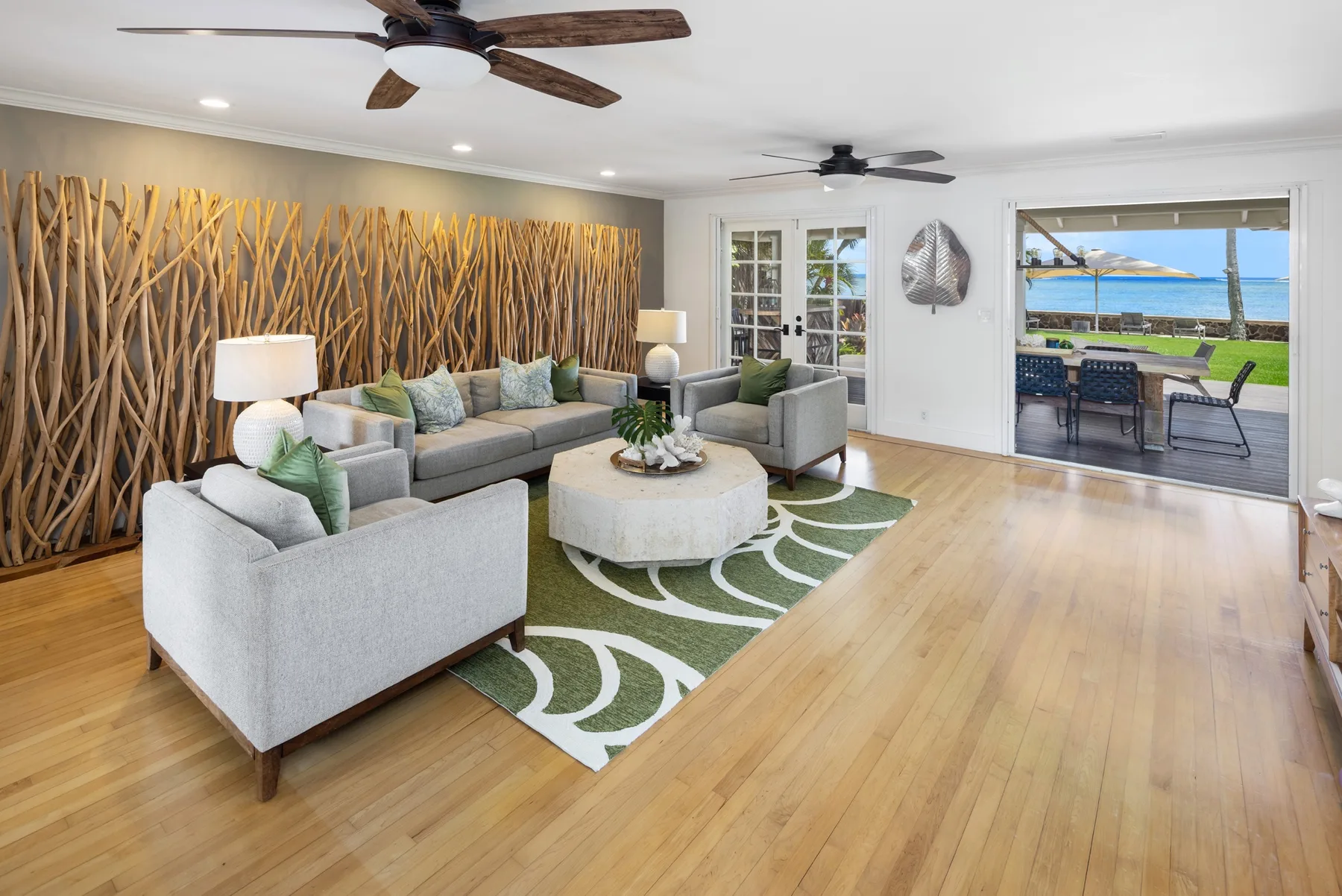 A bright living room with seating around a coffee table and an open view to the patio.