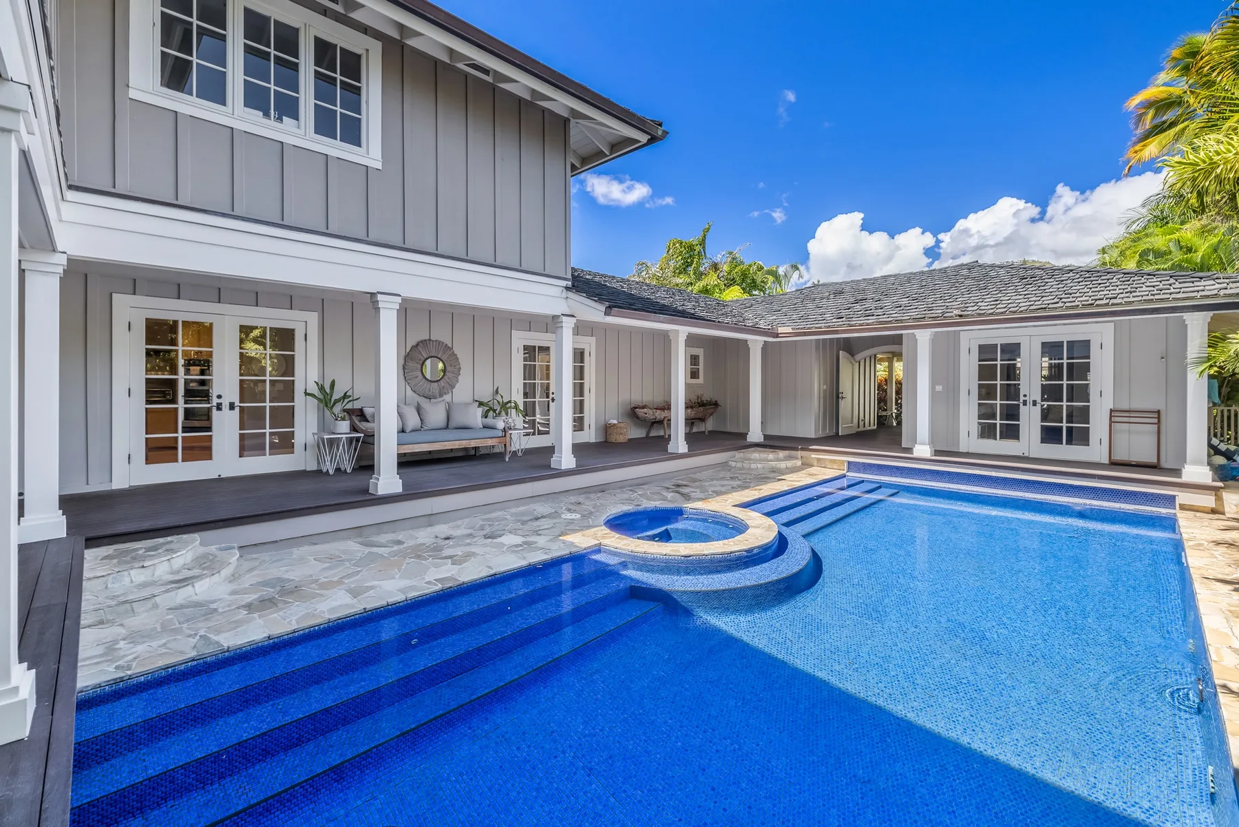 A swimming pool beside a large house, with a small raised circular section.