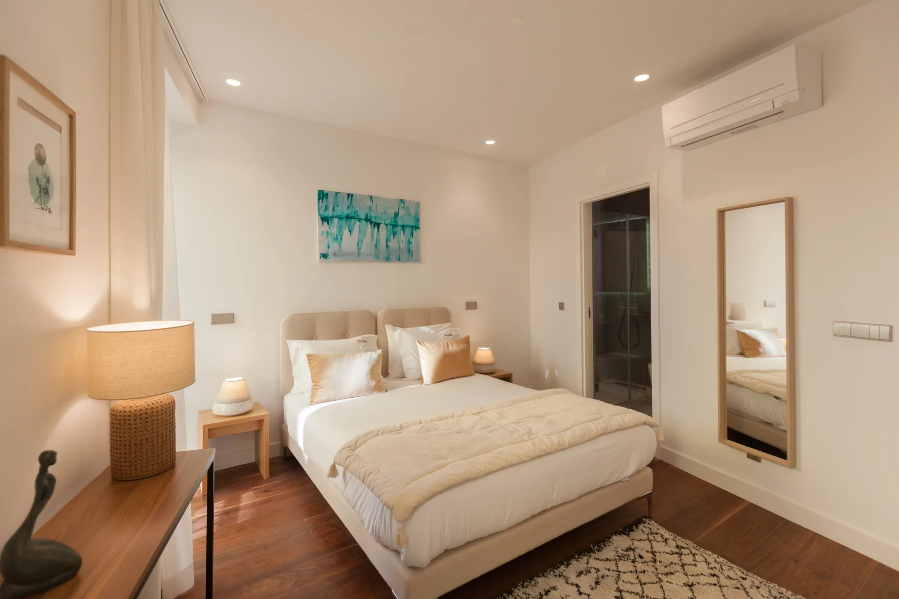 Un dormitorio con una cama doble, mesitas de noche y cuadros enmarcados.