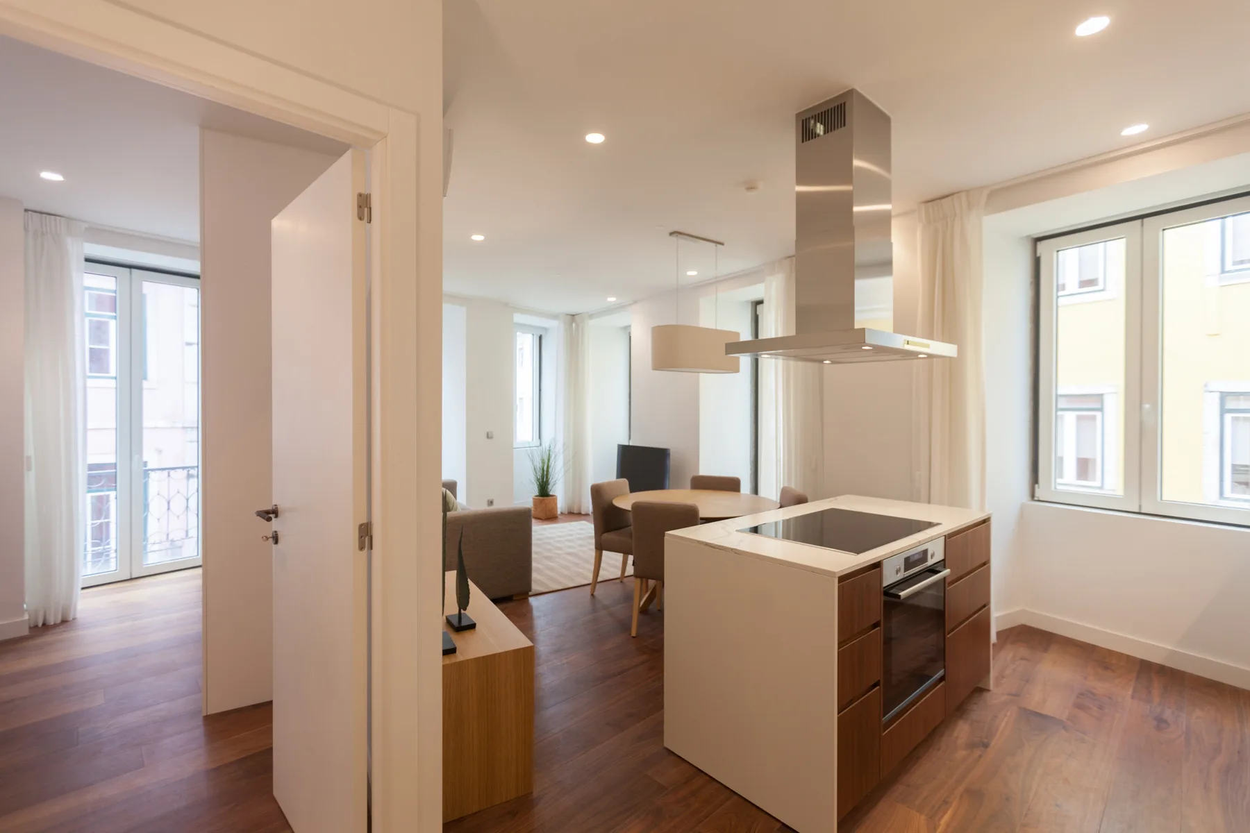 Una cocina y sala de estar de planta abierta con una isla central y ventanas grandes.