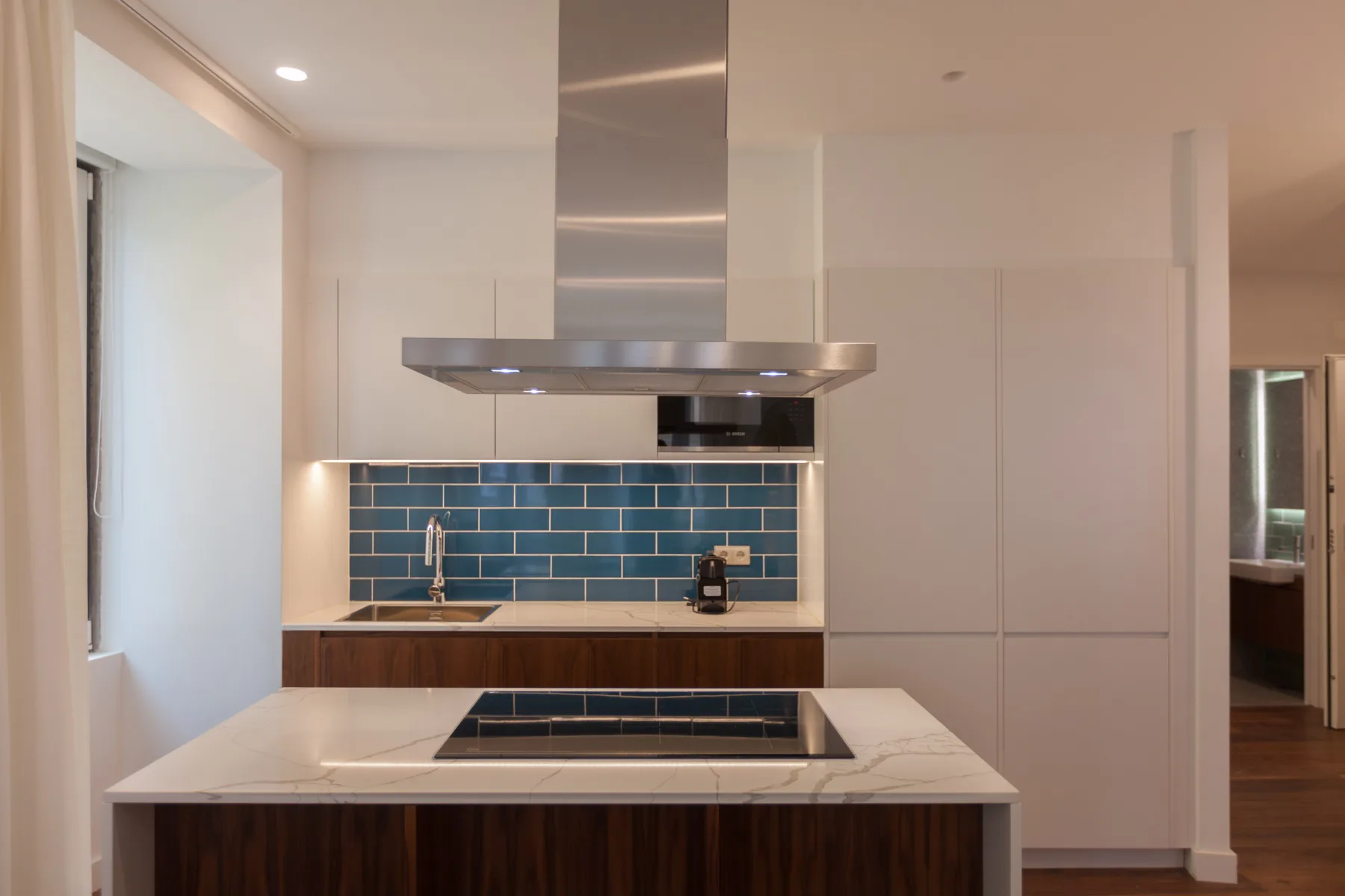 Una cocina moderna con salpicadero de azulejos azules, encimera e isla central.