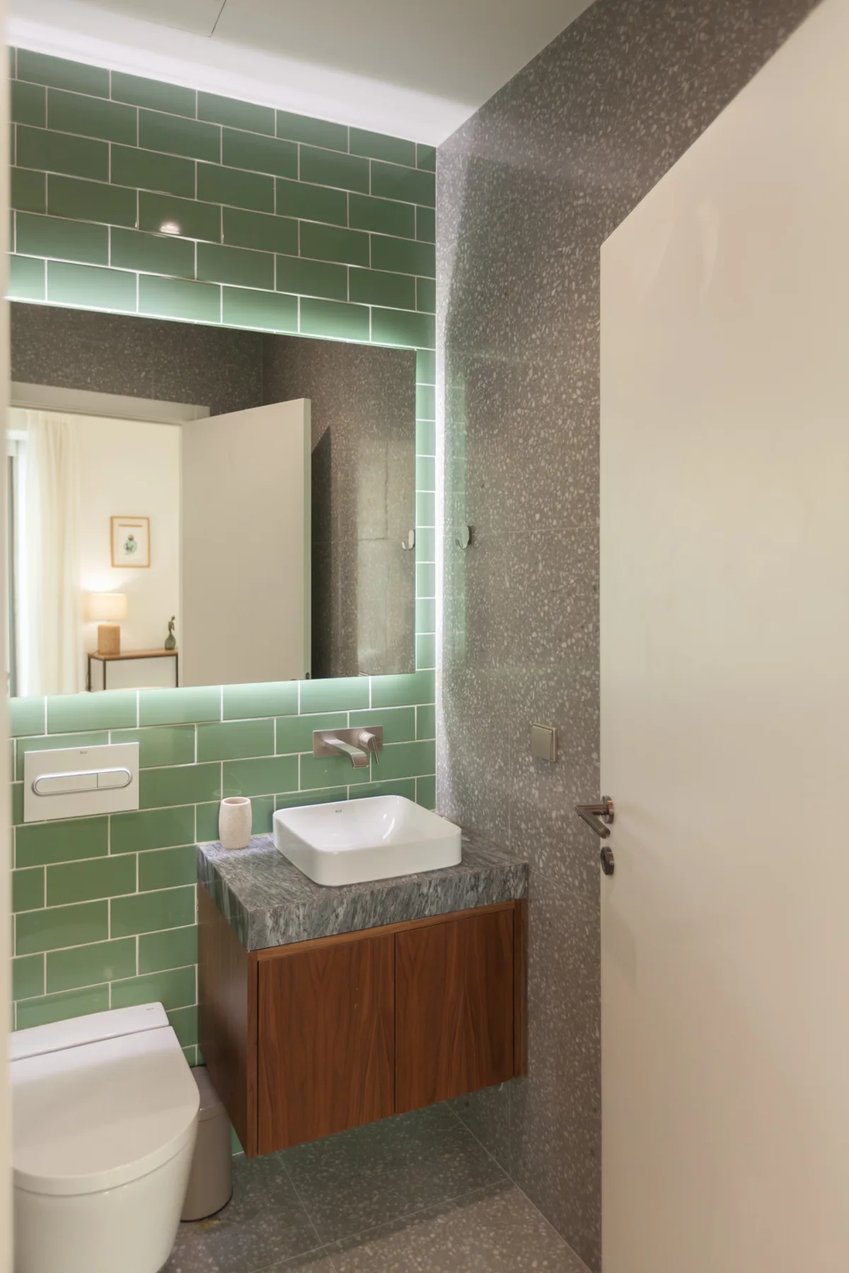 Un baño con una pared de azulejos verdes, un lavabo y un inodoro.