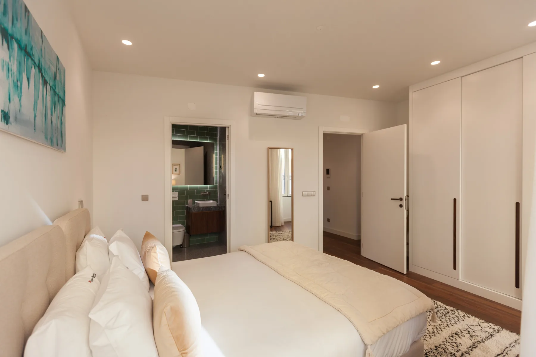 Un dormitorio luminoso con una cama, ropa de cama clara y armarios empotrados.