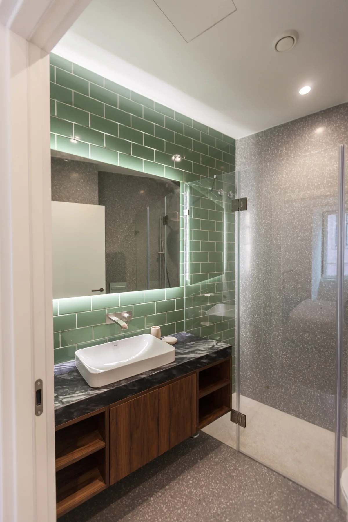 Tocador de baño con lavabo sobre encimera y espejo iluminado.