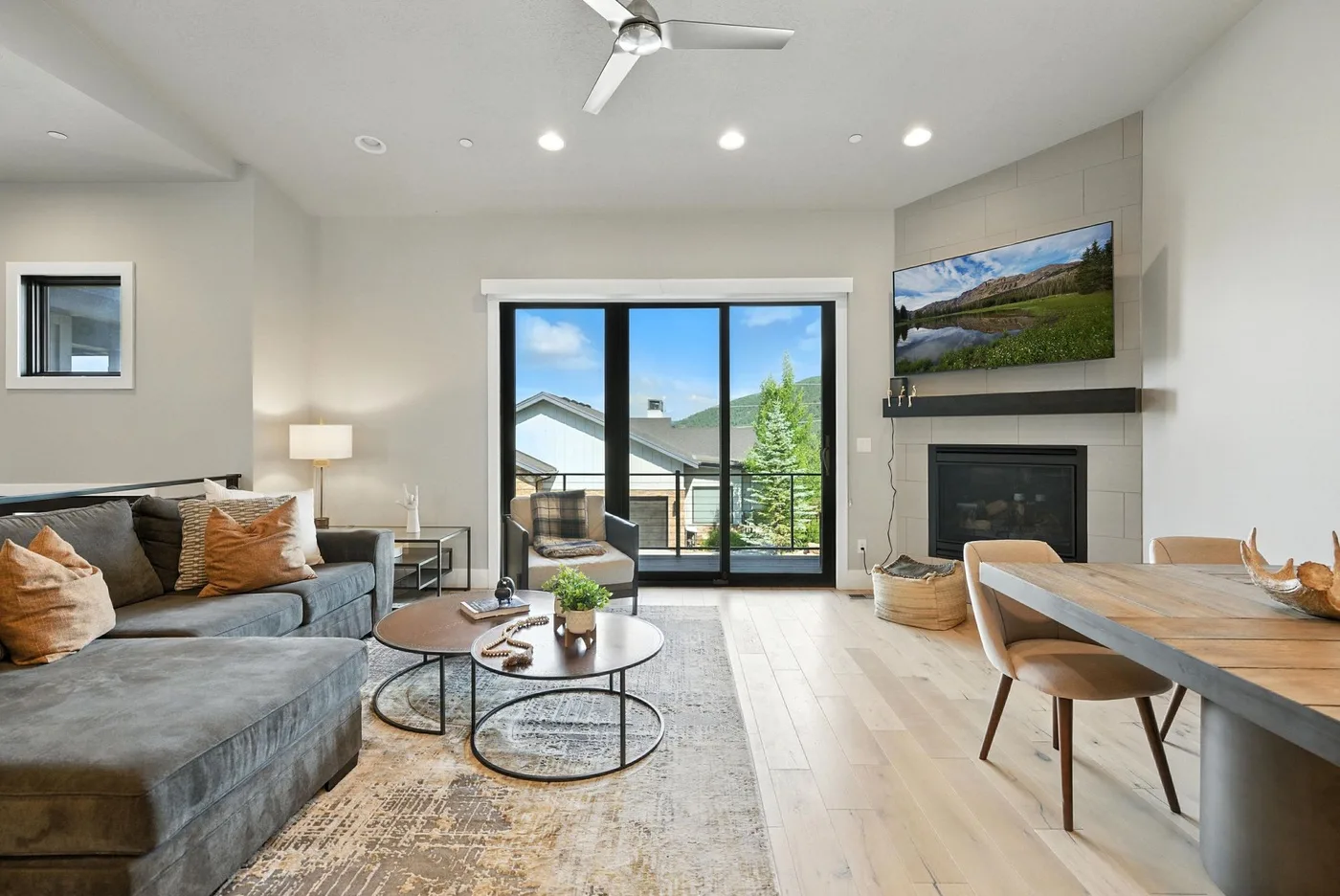 A bright living and dining area opens onto a balcony through large glass doors.