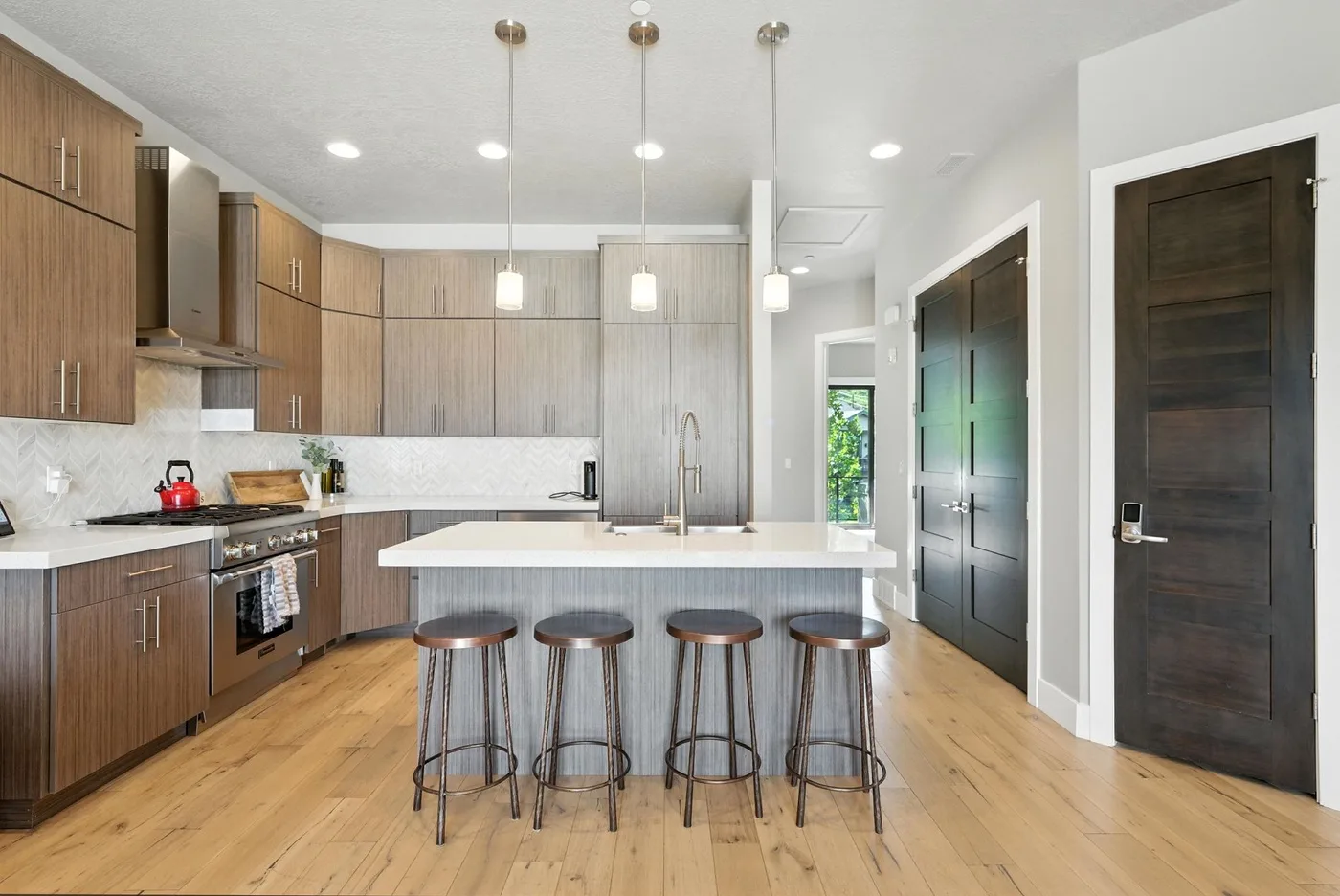 A modern kitchen with wood cabinetry, a central island, and bar stools.