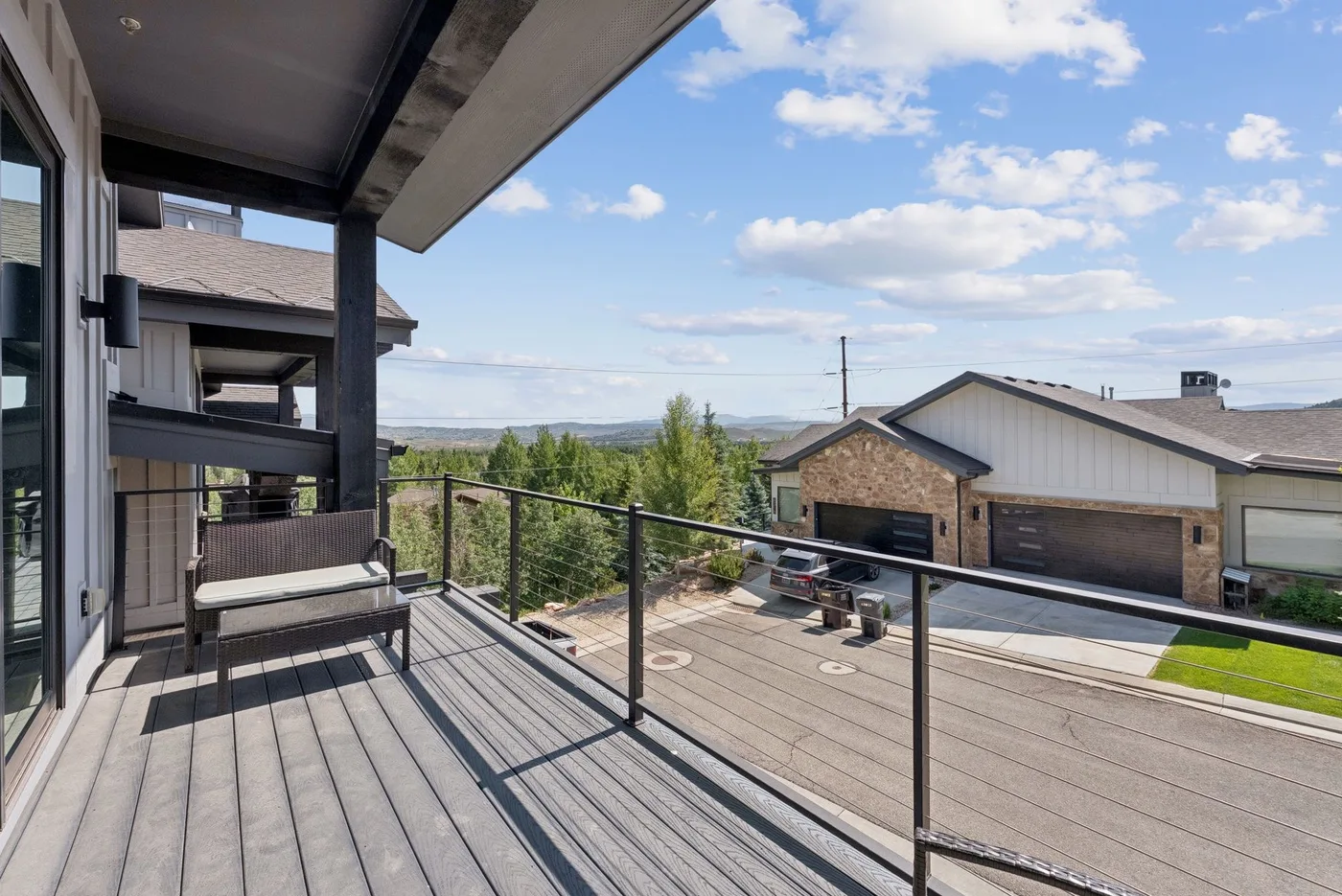 A covered outdoor deck overlooks neighboring houses and a distant landscape.