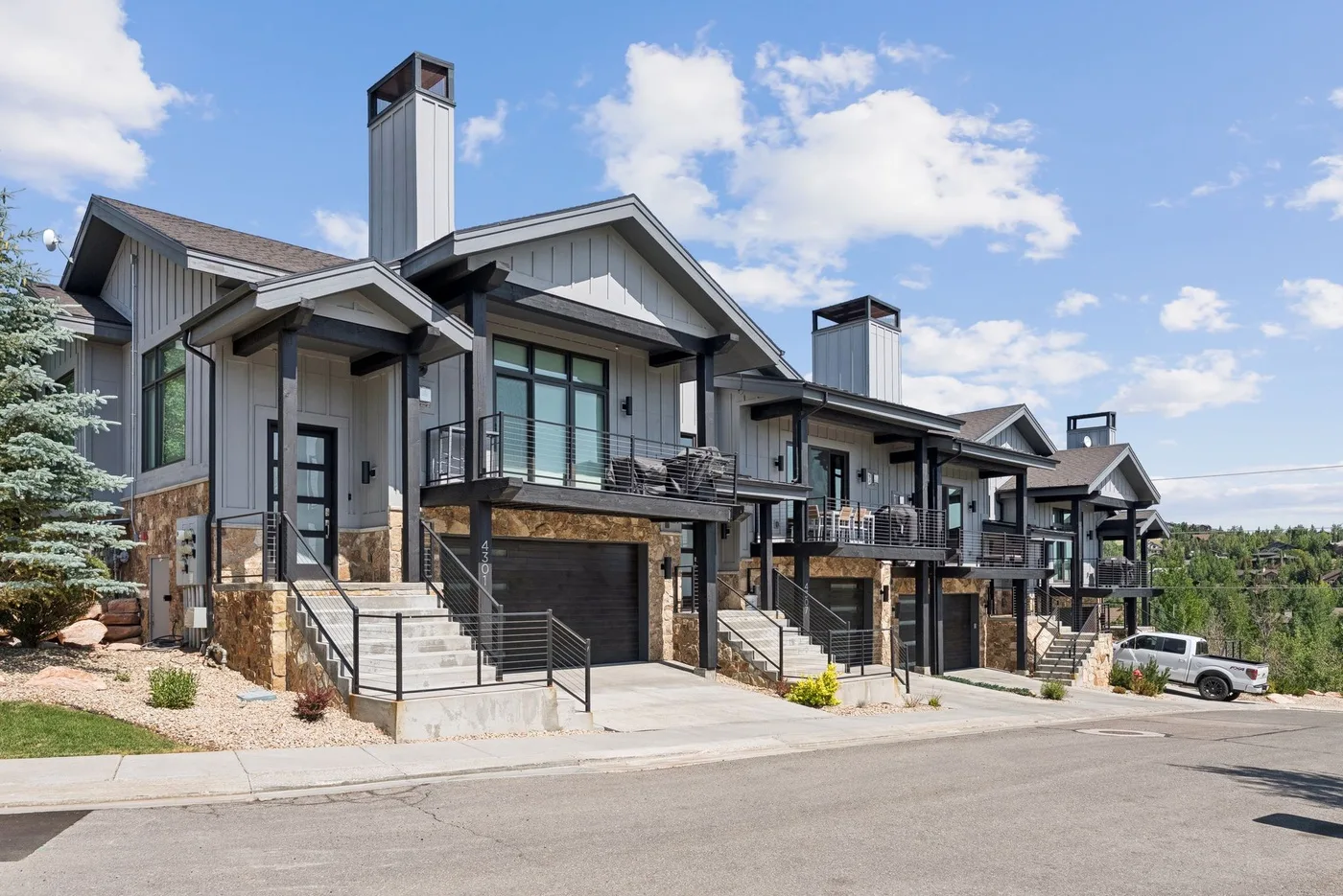 A row of modern homes with balconies and garages faces a paved street.