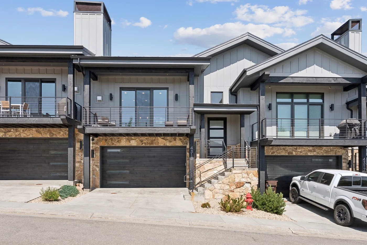 A modern house exterior with balconies, garage doors, and a driveway.