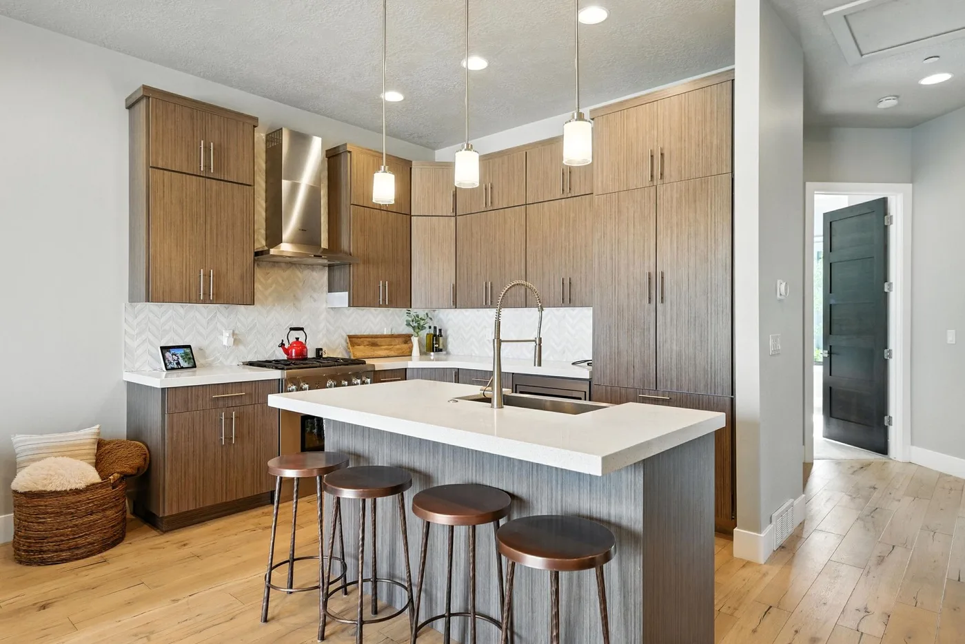 A modern kitchen with a large island, bar seating, and pendant lights.