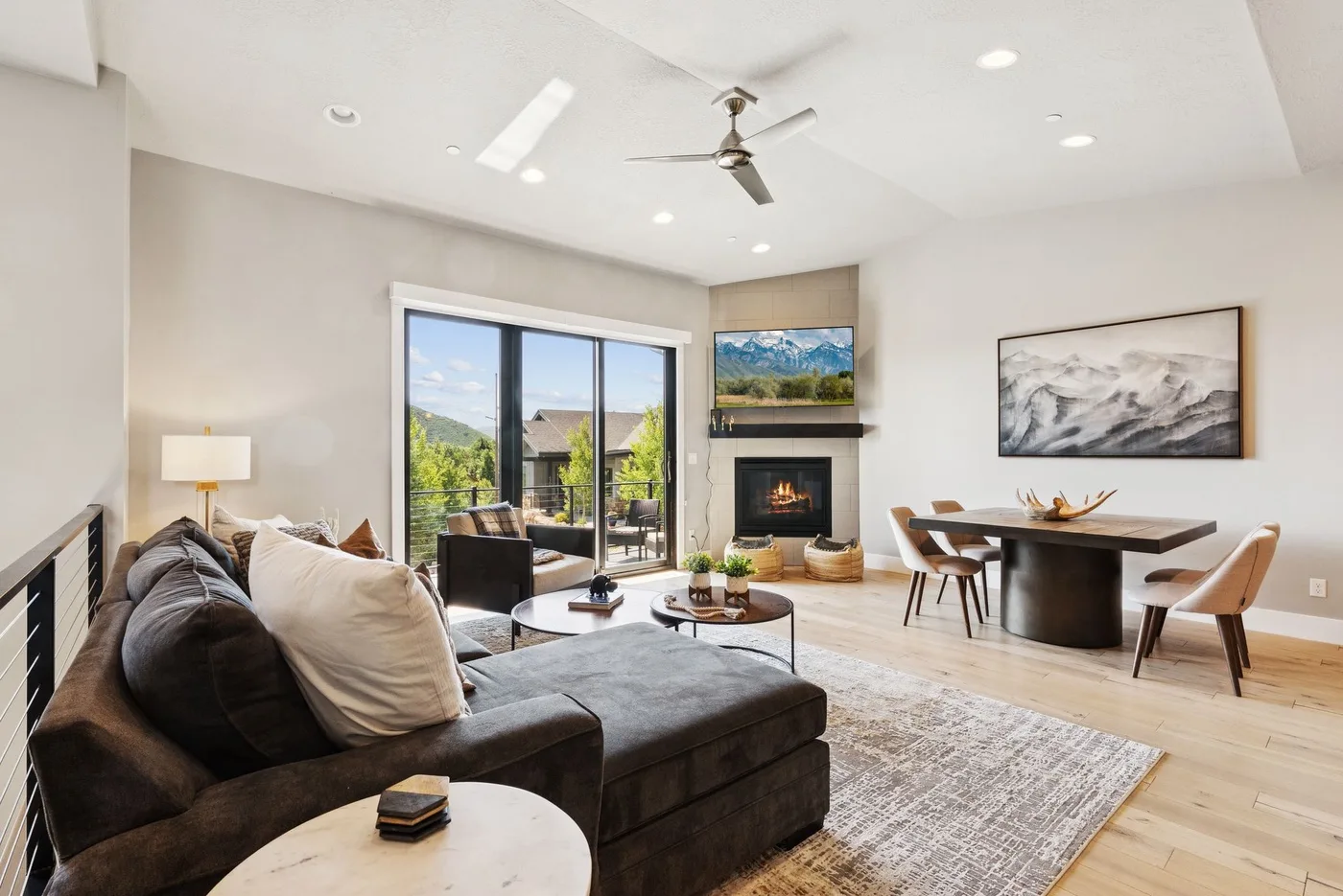 A bright living and dining area features a fireplace and large windows.