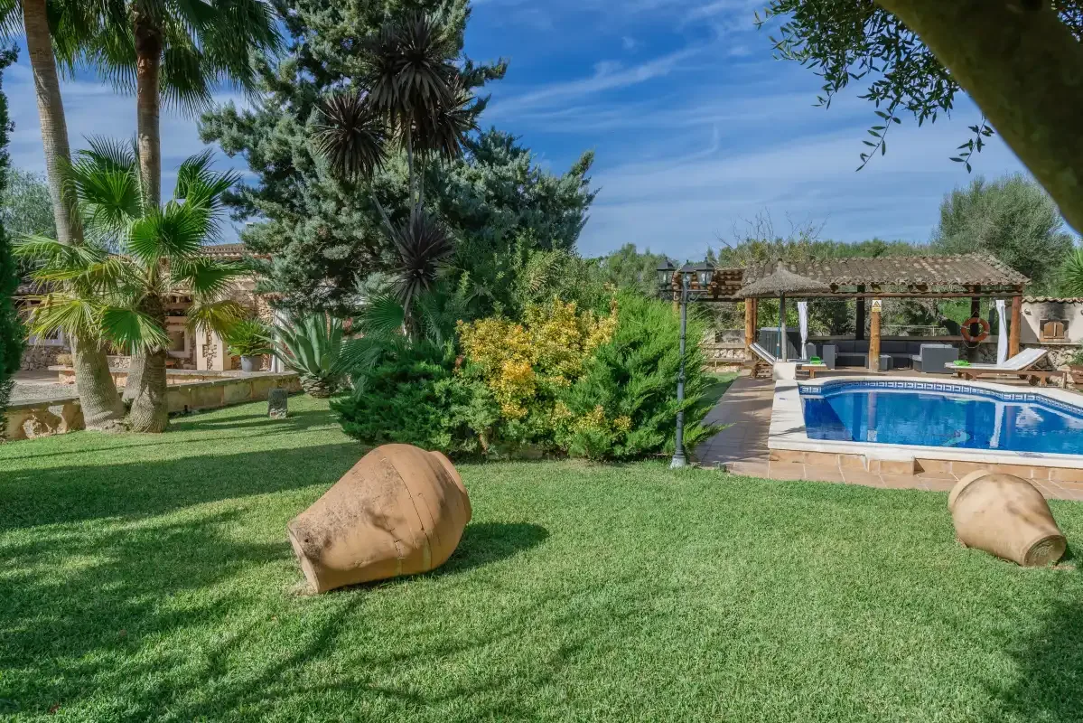 Un jardín con césped, una piscina y árboles frondosos.