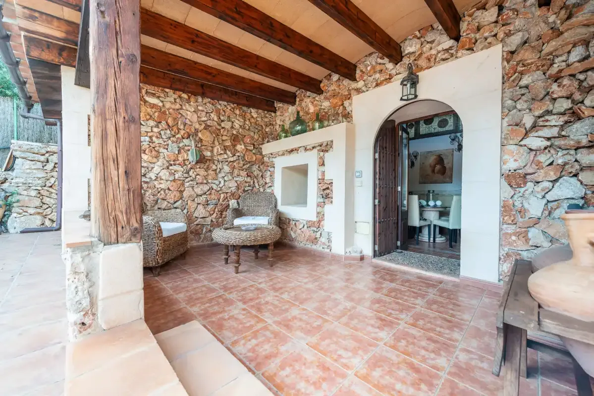 Un interior rústico de piedra con vigas de madera vistas y una zona de asientos.