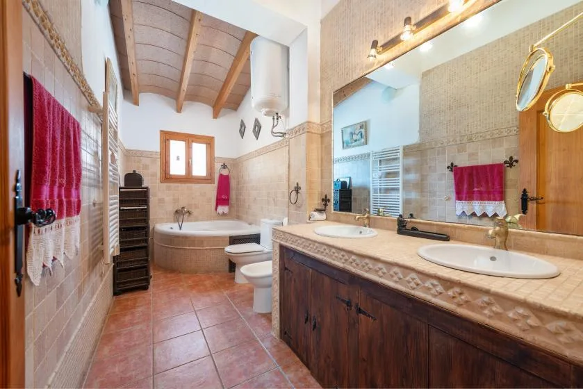 Un baño con azulejos, bañera y un largo mueble con dos lavabos.
