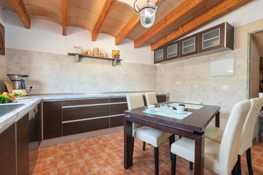 Comedor con una mesa oscura y asientos claros junto a la cocina.