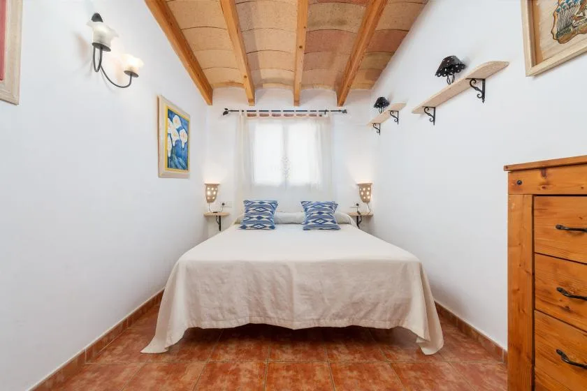Un dormitorio con una cama bajo vigas de madera a la vista.