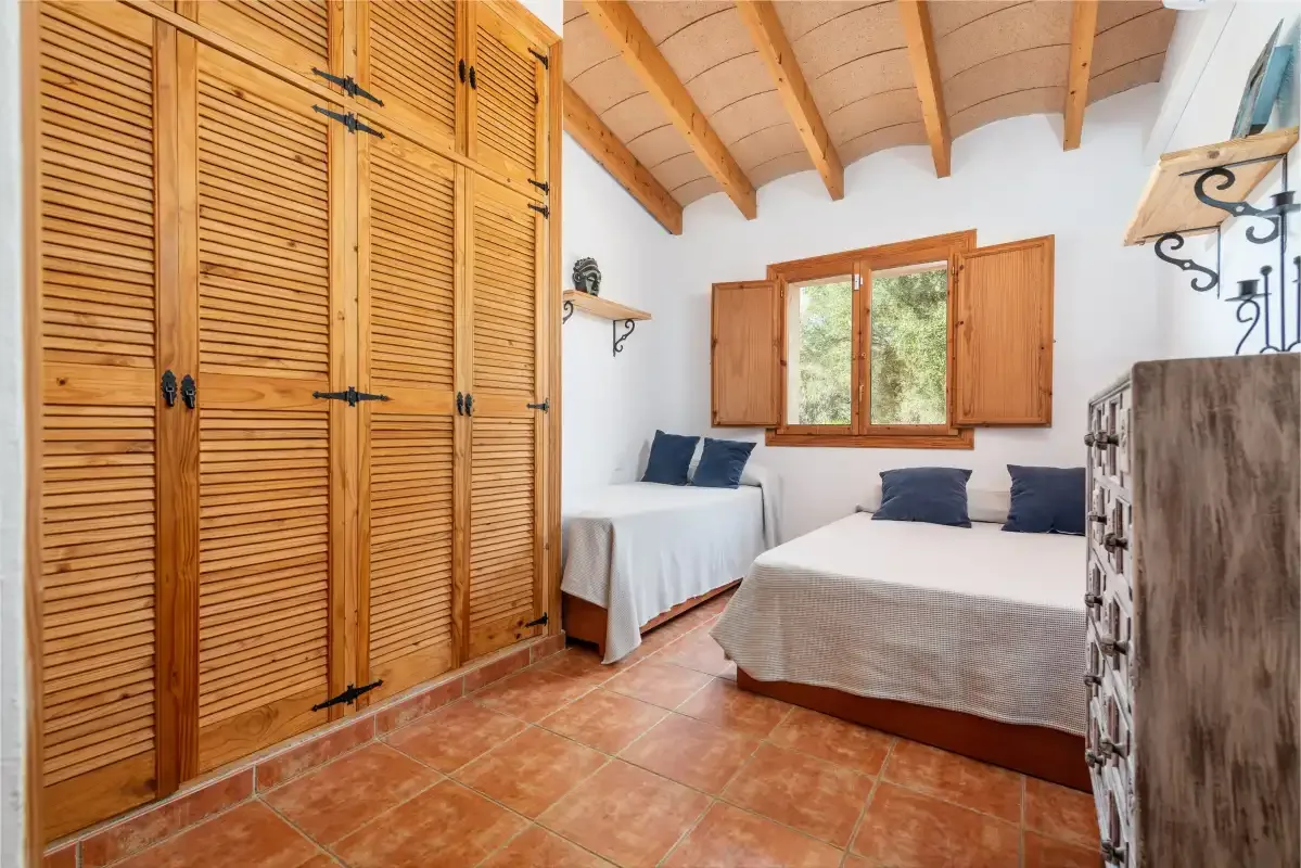 Un dormitorio con dos camas, armarios de madera y una ventana.