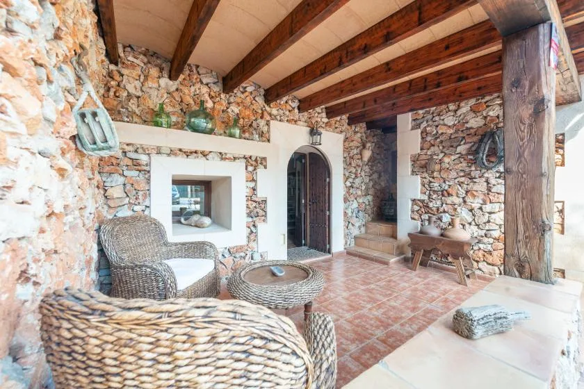 Una sala rústica de piedra con asientos tejidos y vigas de madera expuestas.