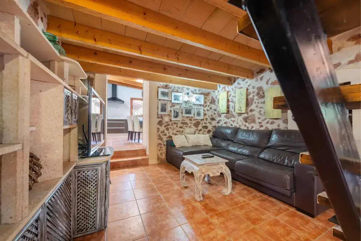 Una sala rústica con asientos oscuros, una mesa baja y vigas de madera vistas.