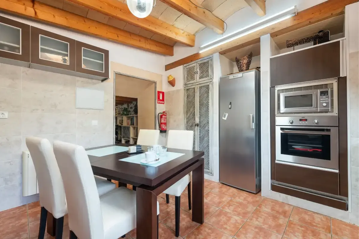 Una cocina y comedor con mesa, asientos y electrodomésticos de acero inoxidable.