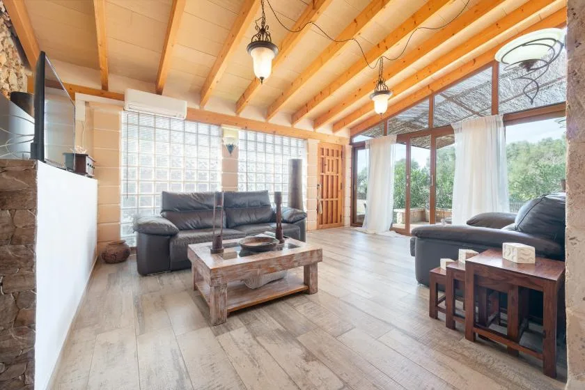Una sala luminosa con asientos, una mesa de centro de madera y ventanales.