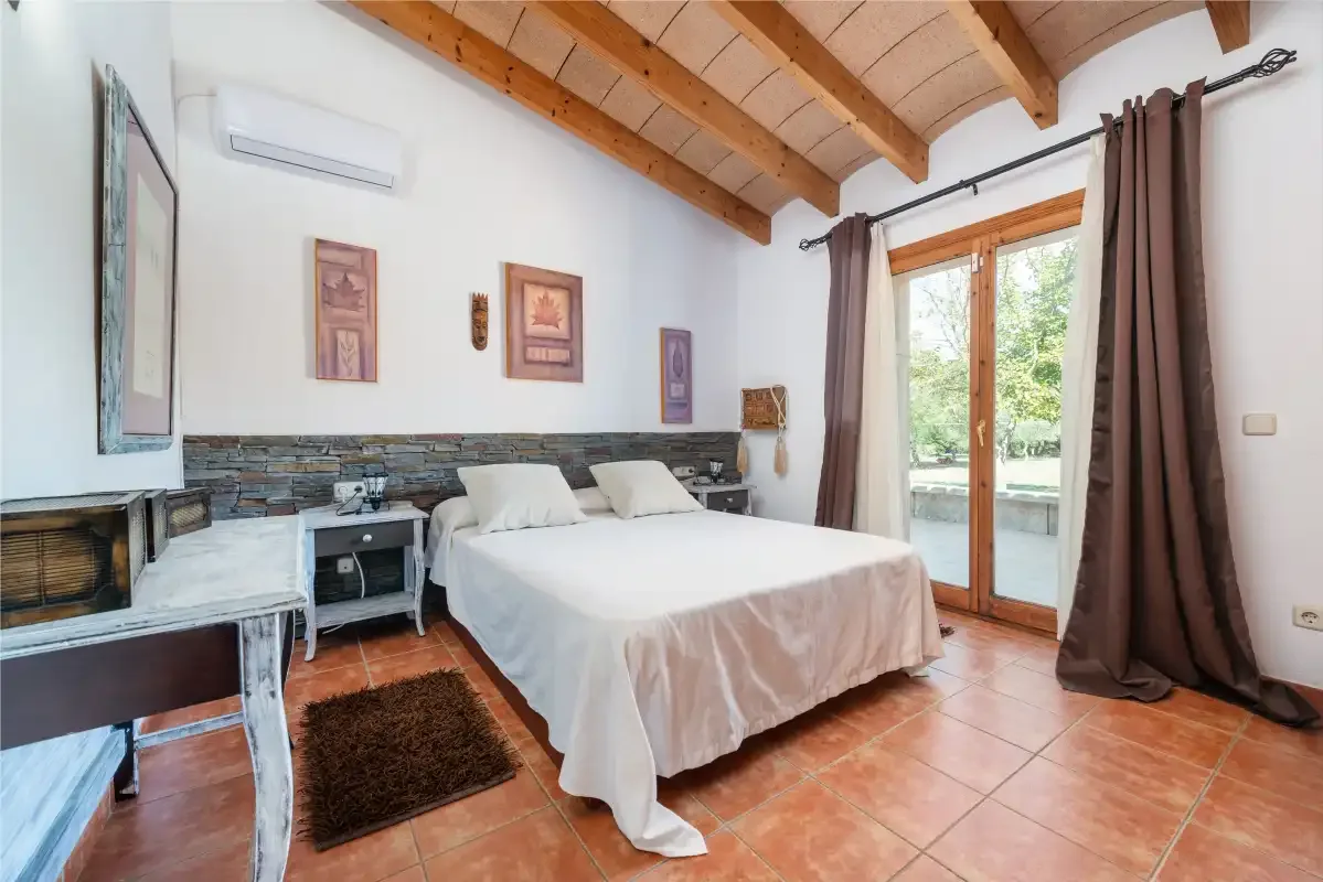 Un dormitorio con una cama grande y puertas de cristal que dan a un patio.