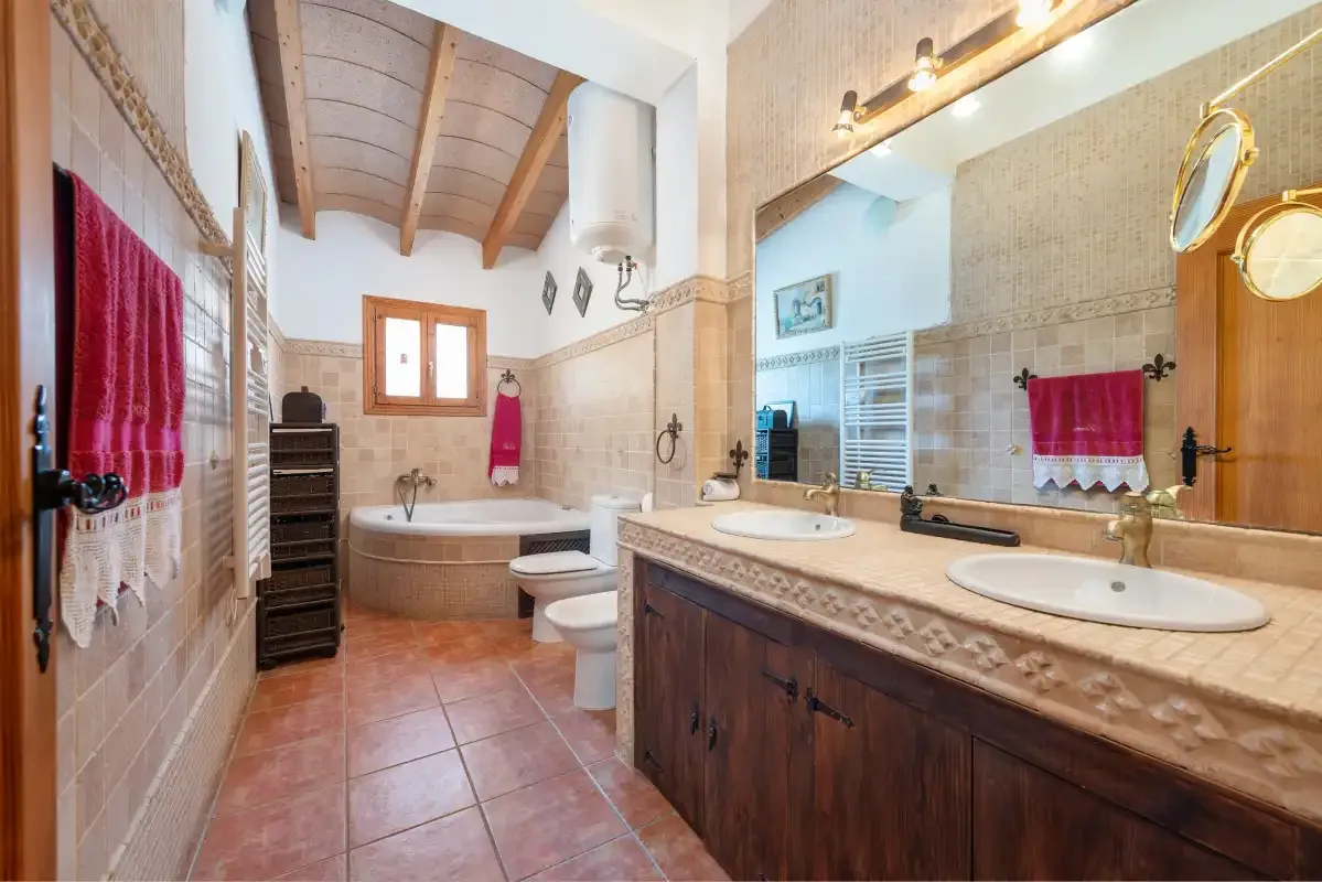 Un baño alicatado tiene una bañera y un tocador largo con lavabos.