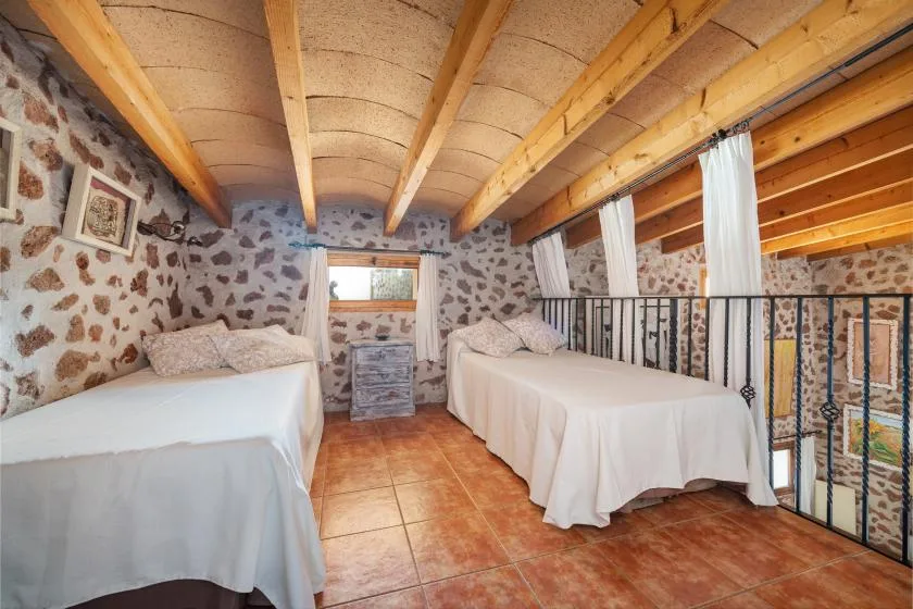 Un dormitorio rústico con dos camas y vigas de madera a la vista.