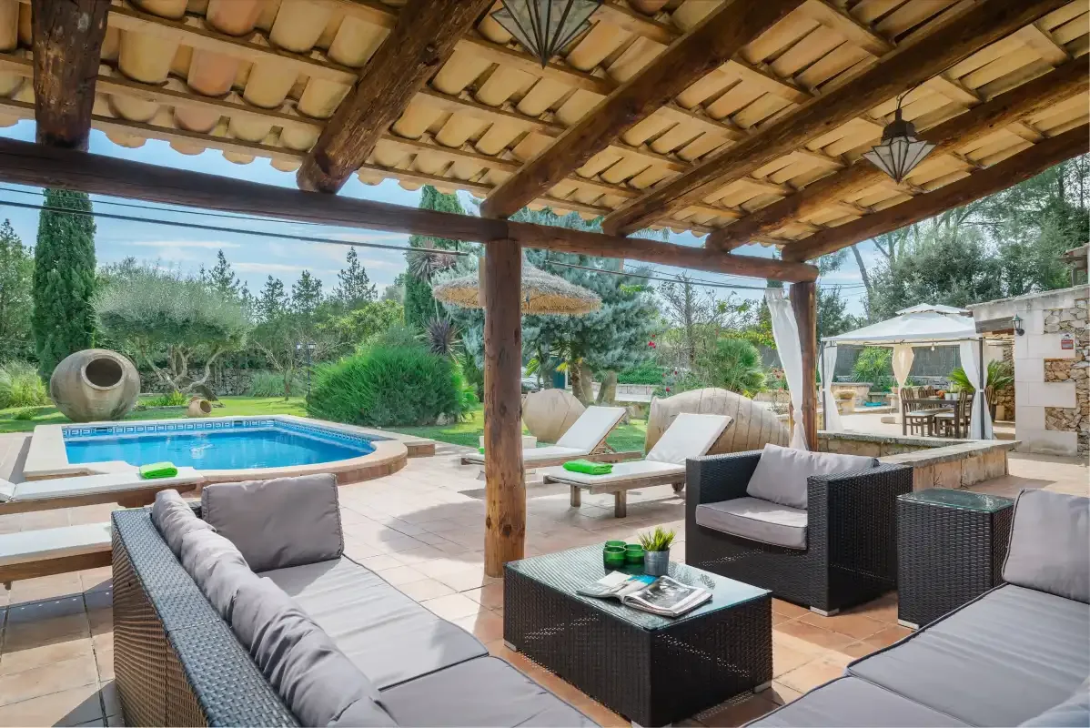 Un patio cubierto con asientos de descanso da a una piscina y un jardín.