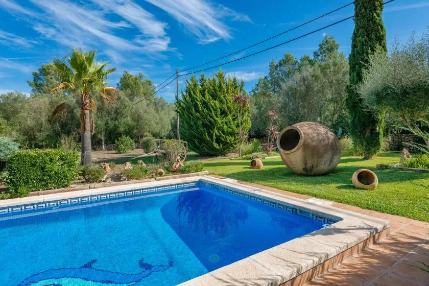 Una piscina junto a una terraza pavimentada y un jardín ajardinado.
