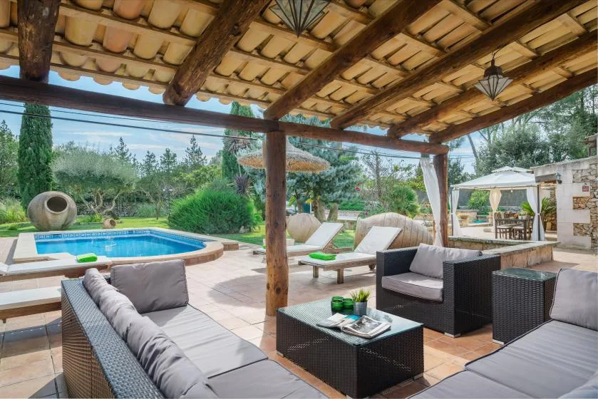Un patio exterior cubierto con asientos de descanso da a una piscina y un jardín.