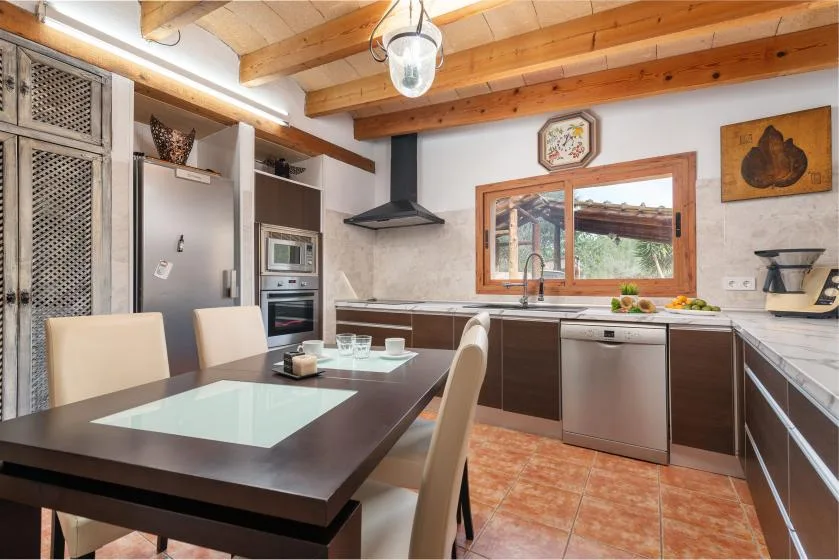 Una cocina con una mesa oscura y vigas de madera en el techo.